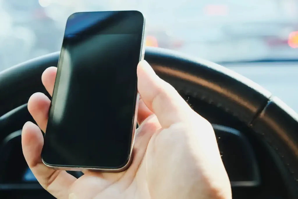 une personne qui tient un téléphone au volant