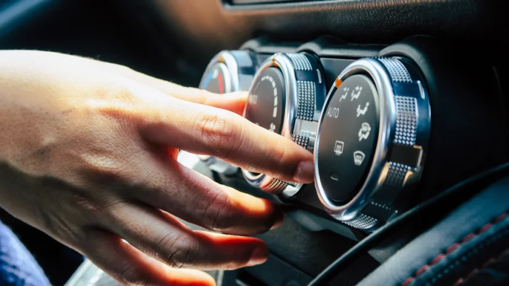 Une personne qui règle la clim d'une voiture