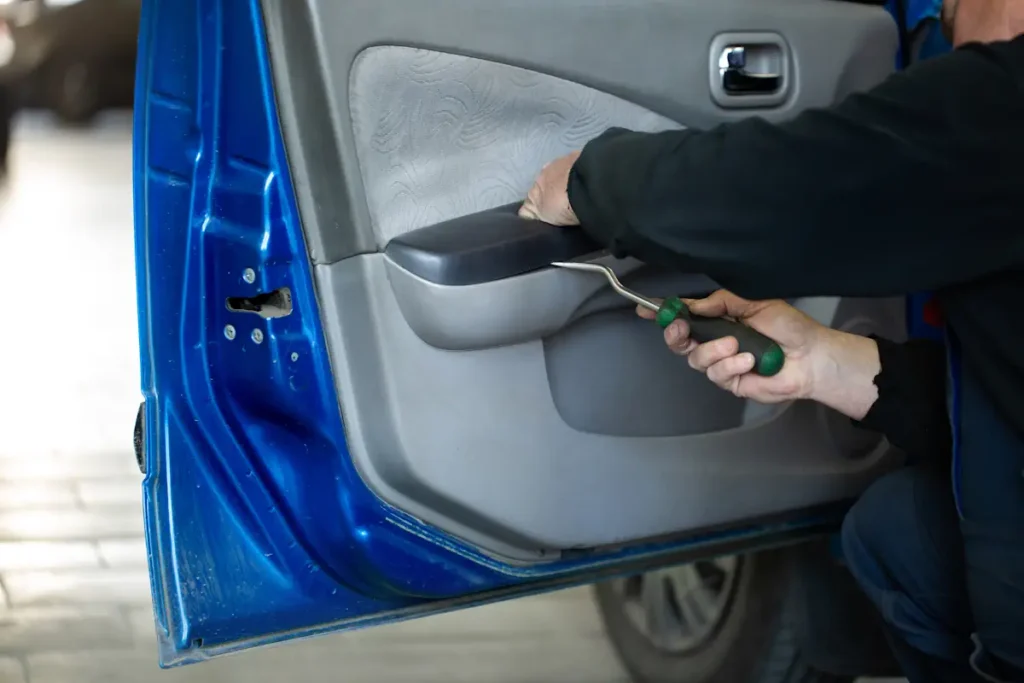 Un homme qui démonte une poignée de porte de voiture