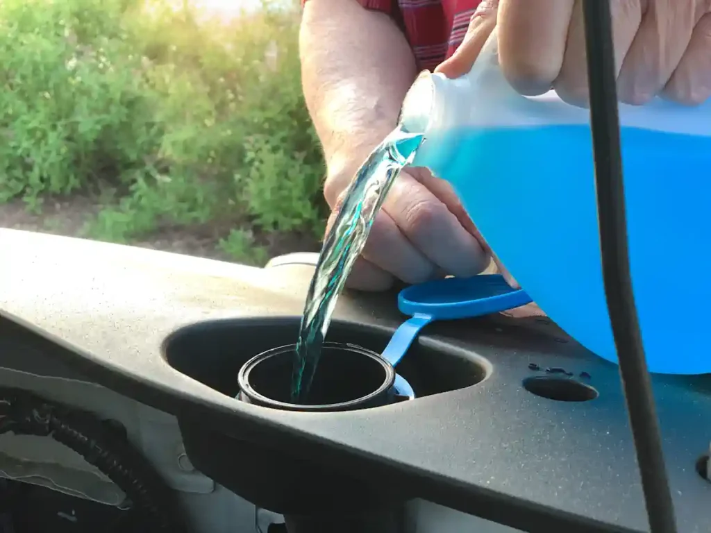 Une personne qui verse du liquide de refroidissement bleu dans son véhicule