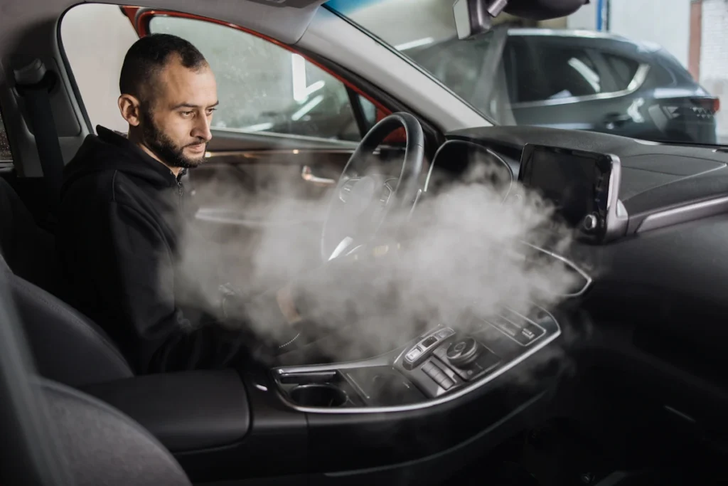 Un homme qui envoie de la vapeur dans l'habitacle d'une voiture