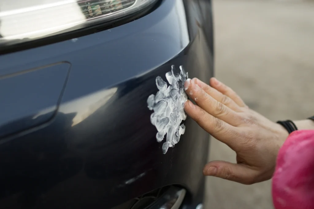 Une personne qui tourne une colle blanche sur la carrosserie d'une voiture