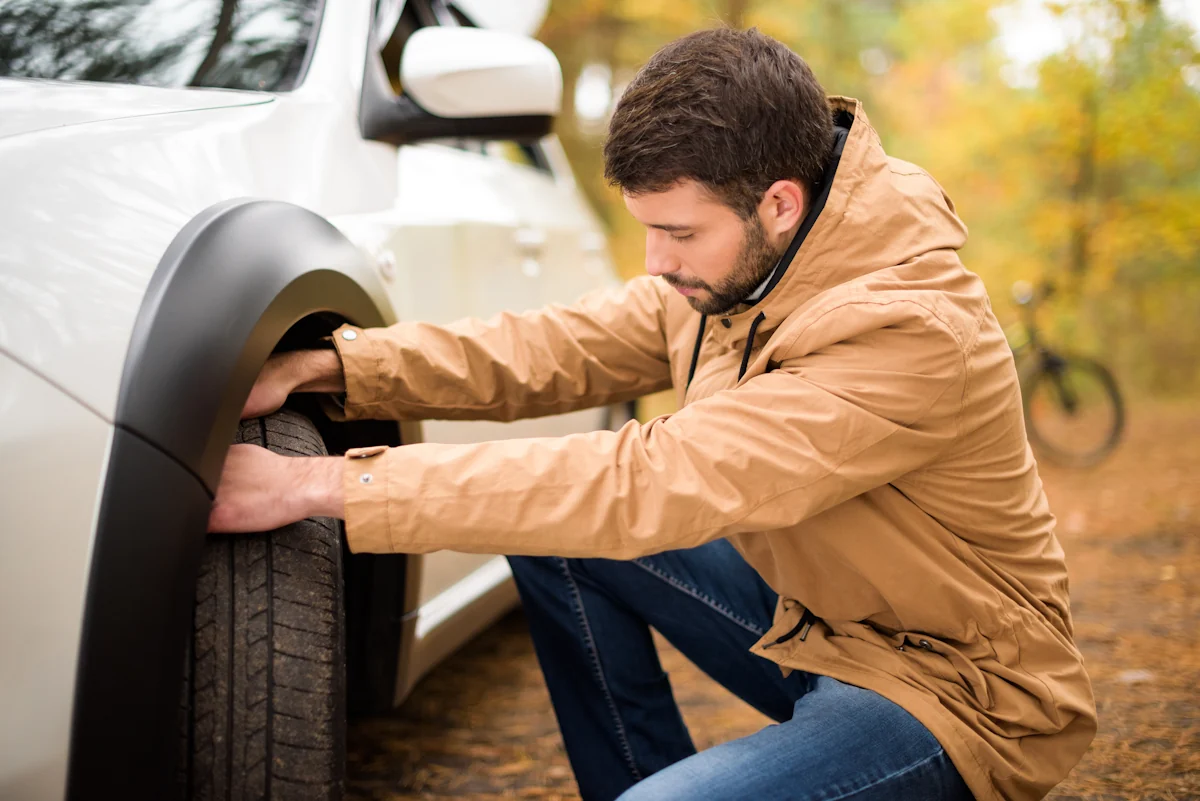 Une personne qui regarde les rainures sur pneu de voiture
